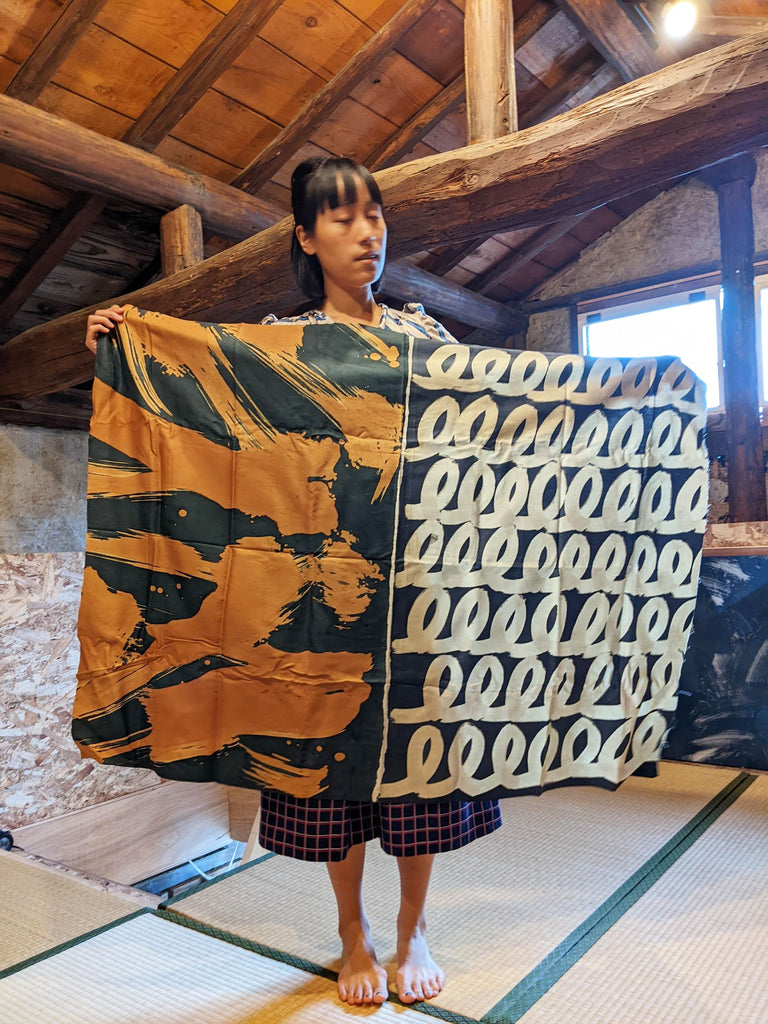 Designer Jenny Lai holds up hand painted fabrics by Takeshi Nakajima