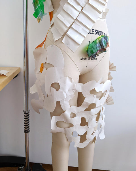 Variety of cut paper swatches pinned to a mannequin