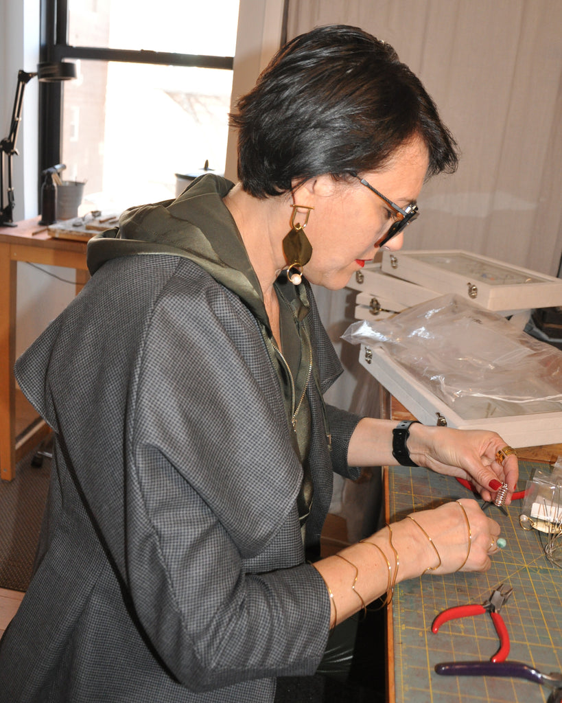 Silvia D'avila working at her jewelry table.