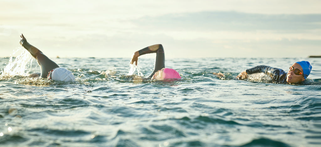 Three swimmers in an open body of water wearing Form swim goggles