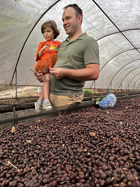 Ricardo holding Lucianna next to drying coffee cherries