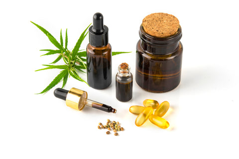 hemp essential oil in small glass bottle. container with cannabis leaves and cannabis seeds on white background.