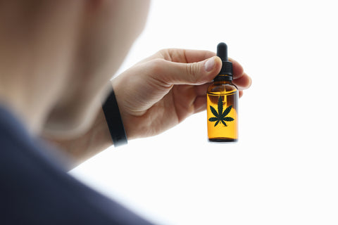 Man holds bottle of marijuana oil in his hand