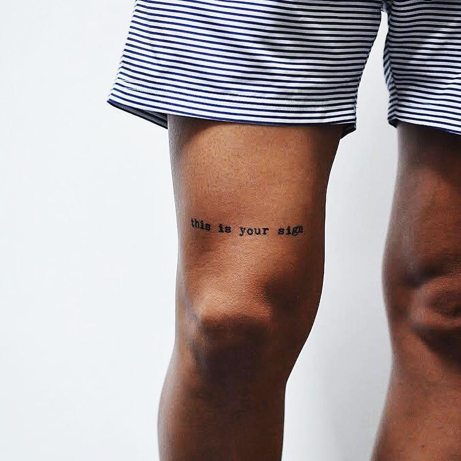 Worthy  mirror writing tattoo on the thigh