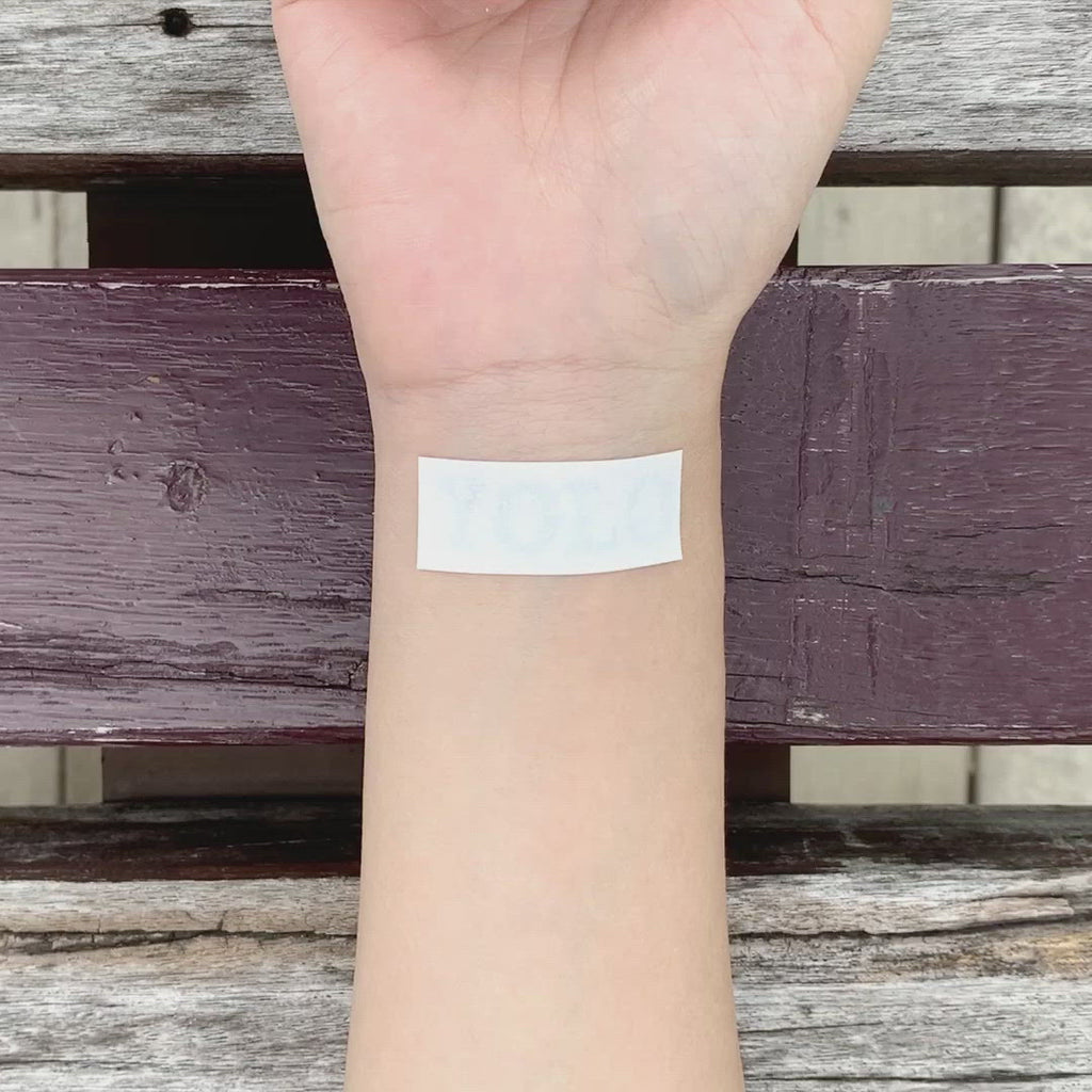 fake small yolo lettering temporary tattoo sticker design idea on wrist