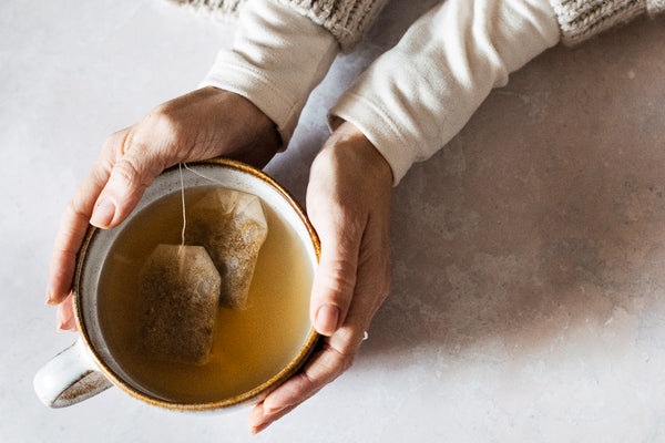 hands holding cup of chamomile, honey & ginger skin boost infusion