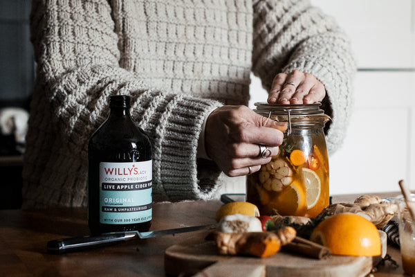 person closing jar of fire cider ready for brewing, surrounding by ingredients