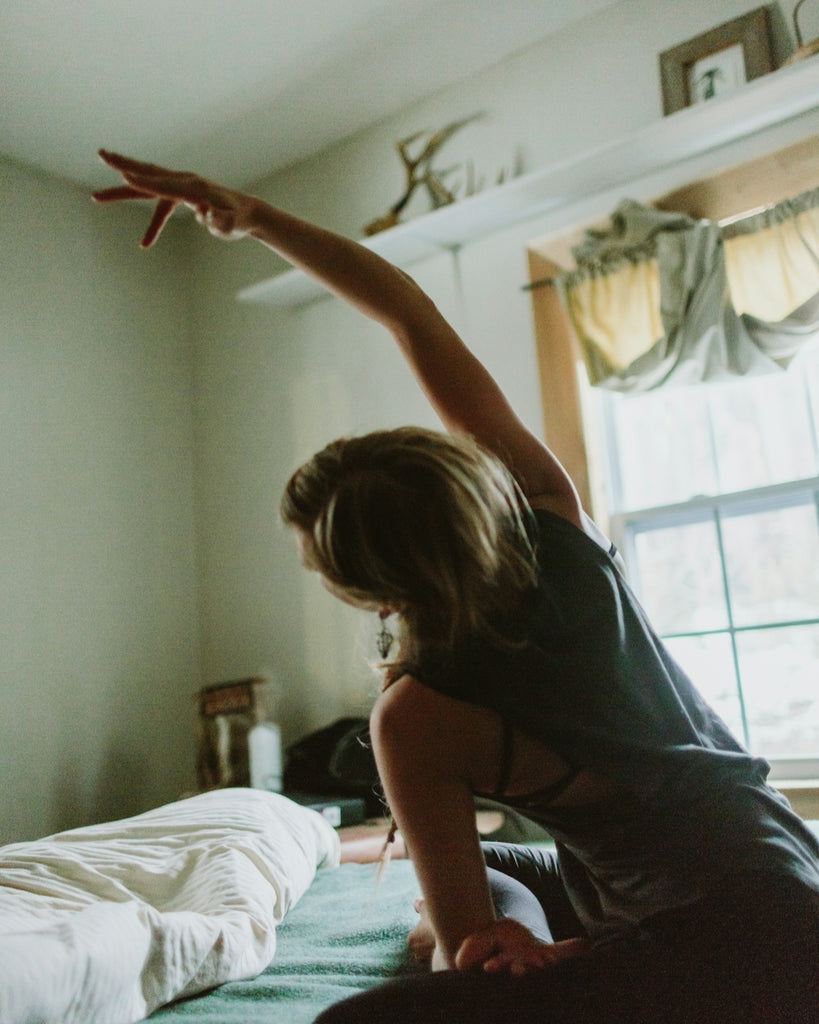 Female practising yoga in a gentle bedroom setting. A great practice for your natural wellbeing toolkit