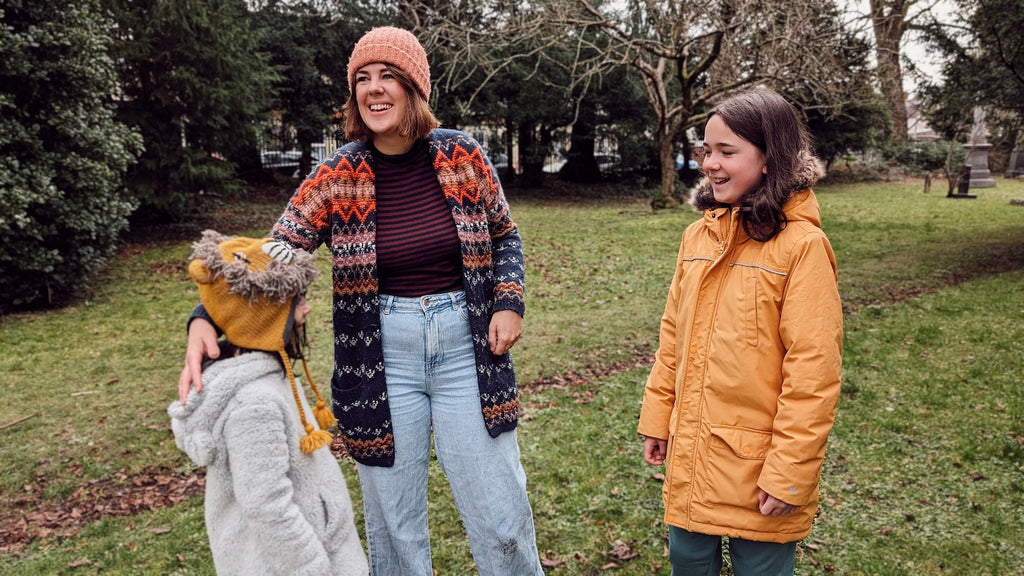 Family laughing together outdoors wrapped up cosily in hats and coats for the cold weather