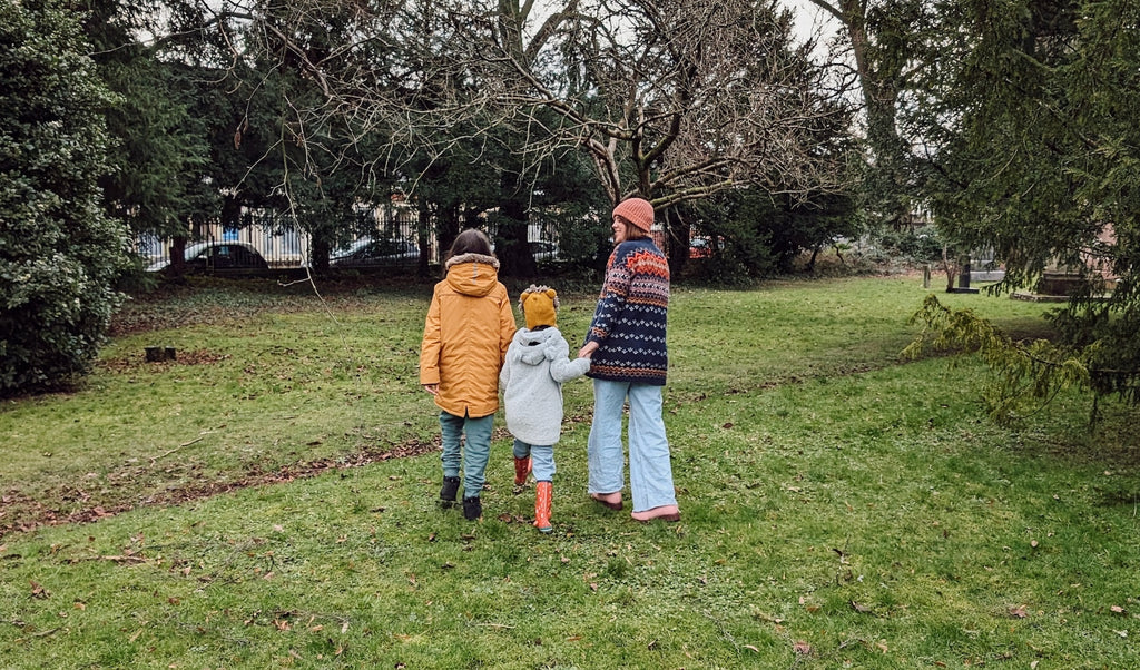Family dressed warmly outdoors in a green area geocaching