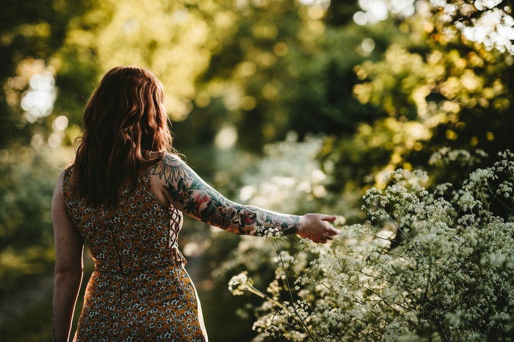 faceless portrait of a woman in dappled sunlight embracing nature for mental wellbeing and joy