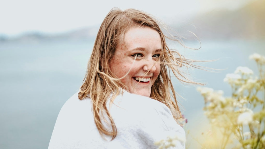 woman smiling light & joyfully overlooking the ocean