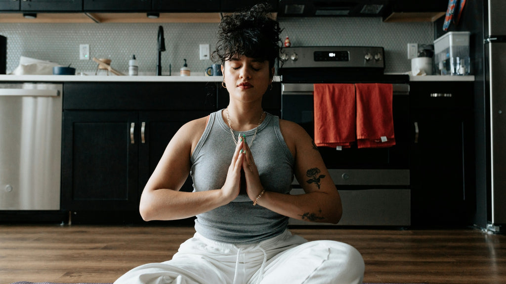 woman looking peaceful in meditation pose on a kitchen floor