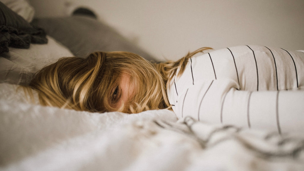 woman lying awake on a bed with hair. tumbling over her face