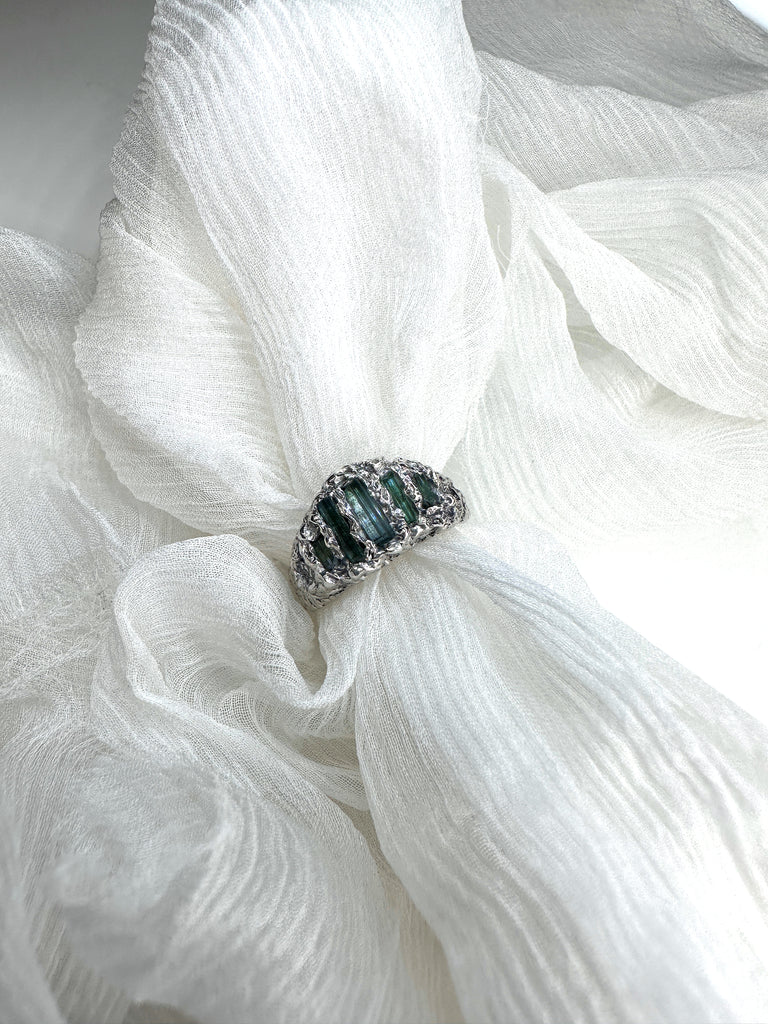 An unusual mountain shaped ring set with uncut rectangular tourmalines. The textured setting and band were stitched in silk and then cast in silver.