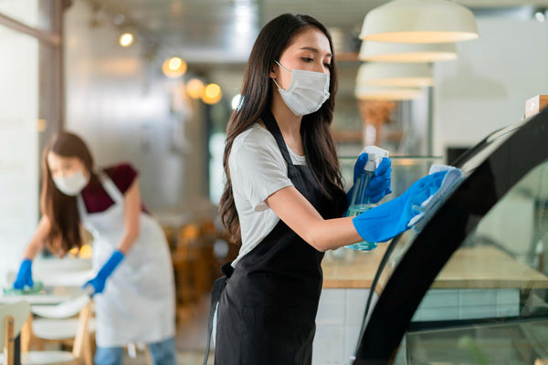 Woman cleaning a restaurant using cleaning supplies