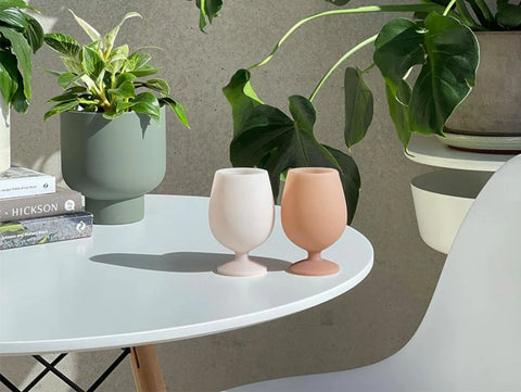 silicon wine glasses on a table with plants around them