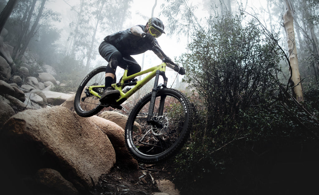 a cyclist riding a YT mountain bike through a forest