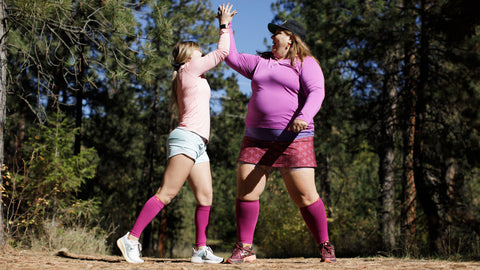 two women in compression socks high fiving