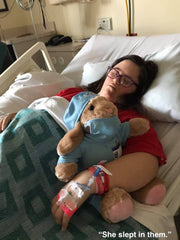Ellie asleep in Children's Mercy hospital after heart surgery wearing a red AudreySpirit shirt and hugging a teddy bear