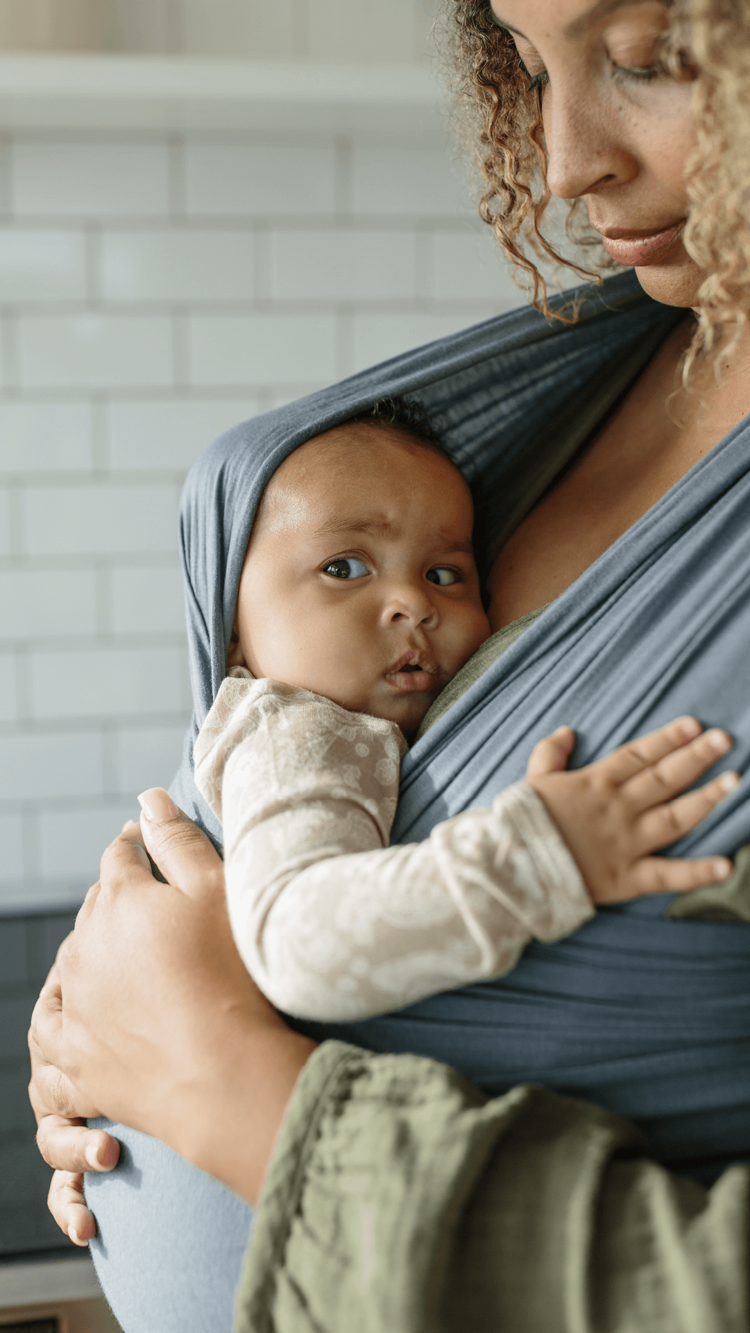 Baby giving "side eye" glance at the camera being held in the Solly Wrap in Swell