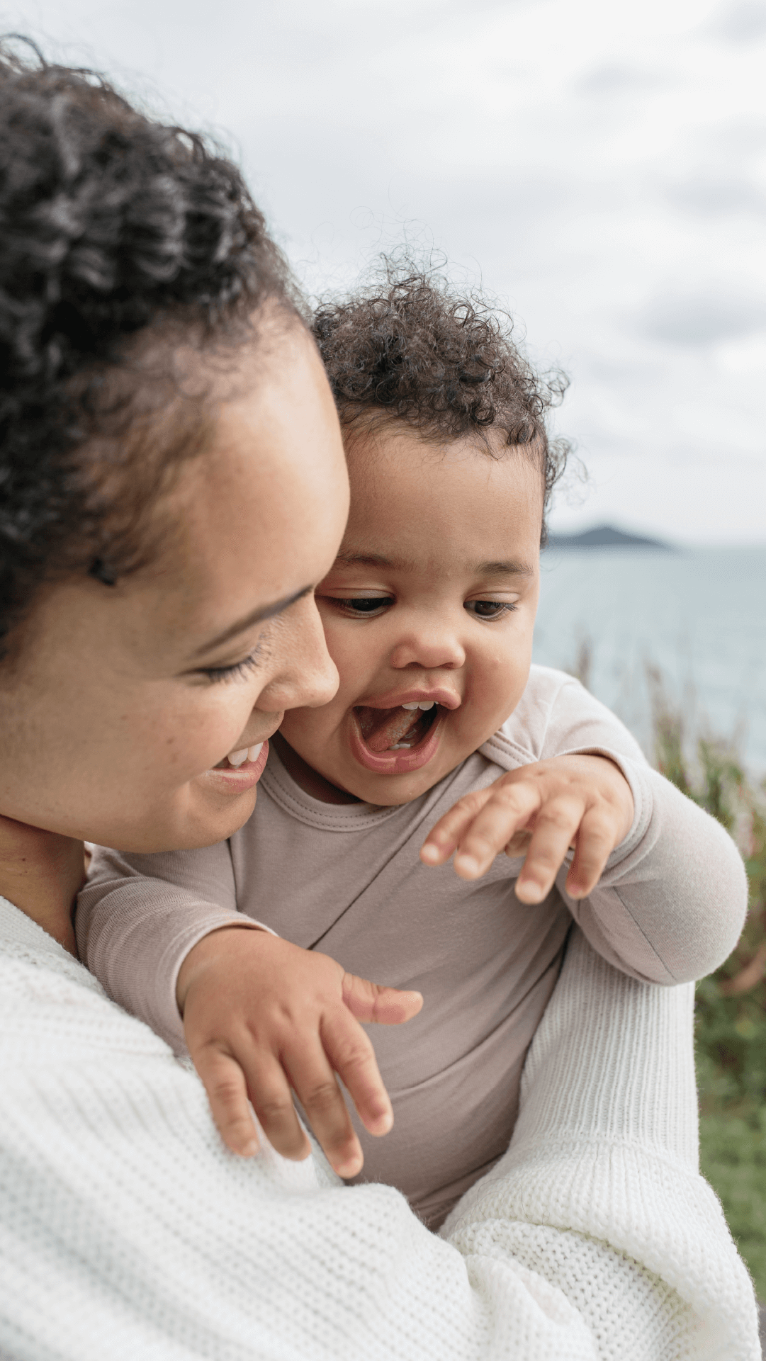 Smiling baby with chubby cheeks being held by smiling mom