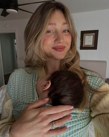 Woman smiling while taking a selfie with sleeping baby in the Picnic Solly Wrap