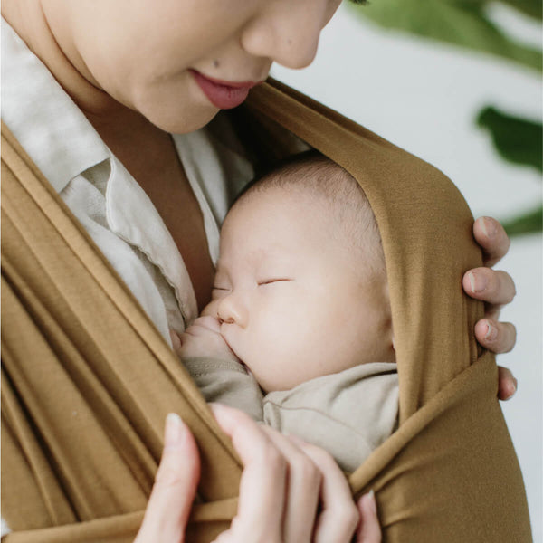 Mother looks down at her sleeping baby in Camel Solly wrap