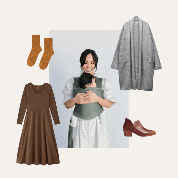Woman carrying baby in a Basil Solly Wrap styled with a brown dress, gray cardigan, socks, and booties