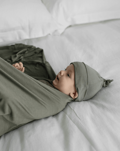 Baby lying down being wrapped in Basil Solly Swaddle