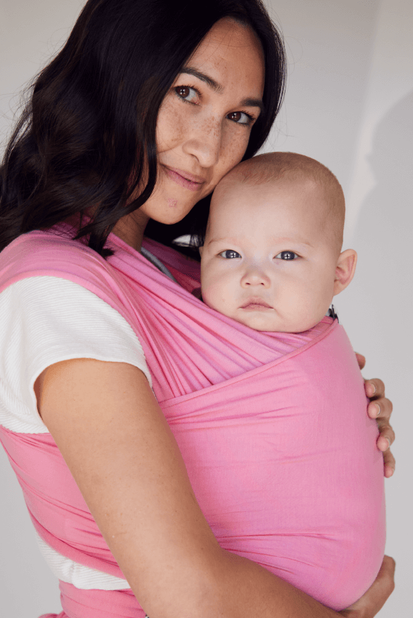 Mother smiling holding her baby in an Iconic Pink Solly Wrap