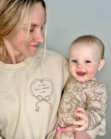 Woman holding baby on her hip, and looking down and smiling at her