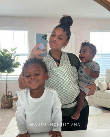 Smiling mom taking a mirror selfie with young son, toddler, and baby wrapped in the Fern Chequer Solly Wrap