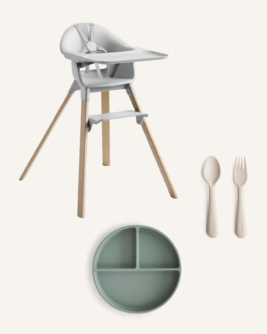 Beige background with gray high chair, green silicon plate, and beige silicon fork and spoon