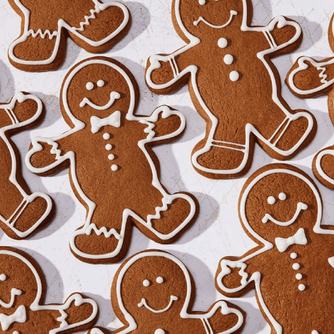 Gingerbread cookies in the shape of a traditional gingerbread man with white frosting eyes, smile, button, and bow tie