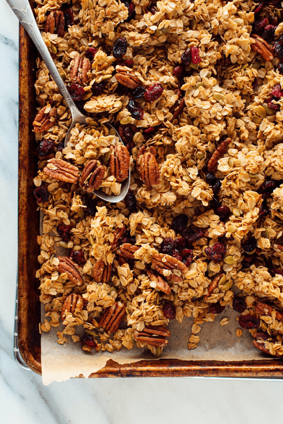 Sheet pan with baked granola and a spoon resting on pan