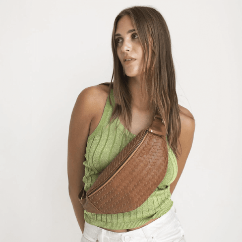 Brunette woman in green tank with a woven leather cross body bag