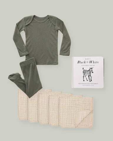 Basil Solly Sleeper with beige muslin burp cloths, and a baby book