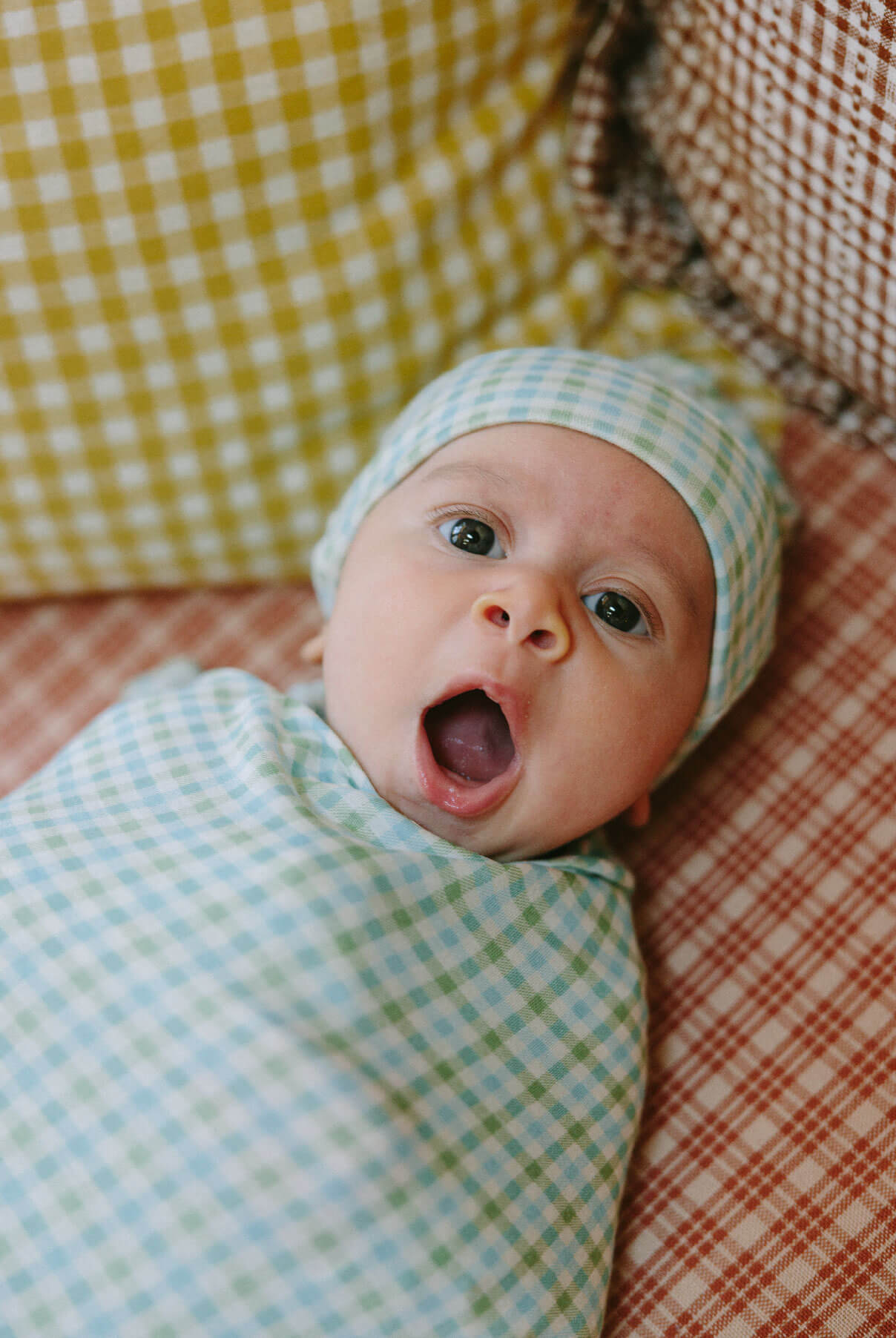 Baby swaddled in a "picnic" patterned Solly swaddle yawns