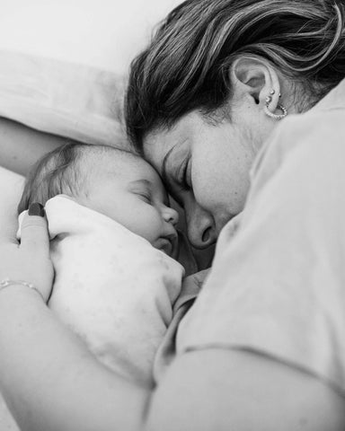Black and white image of mom laying with napping baby face to face