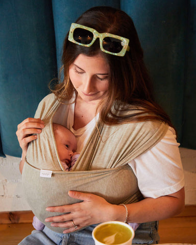 Woman with light skin tone looks down at baby in Matcha Foam Solly Wrap