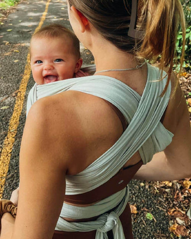 Baby smiles in Solly Wrap while mom is on a trail walk