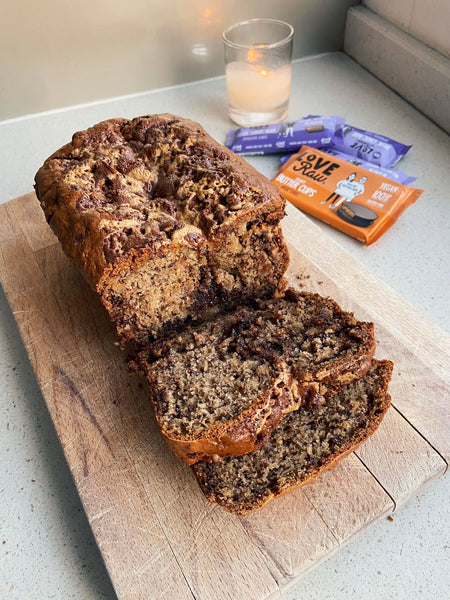 Vegan banana bread cut into slices on a wooden chopping board. Chocolate oozes from the banana bread.