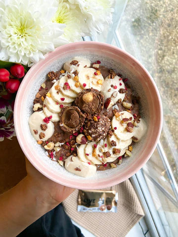 Bowl full of our nutty choc ball oats, topped with hazelnuts and freeze dried raspberry pieces.