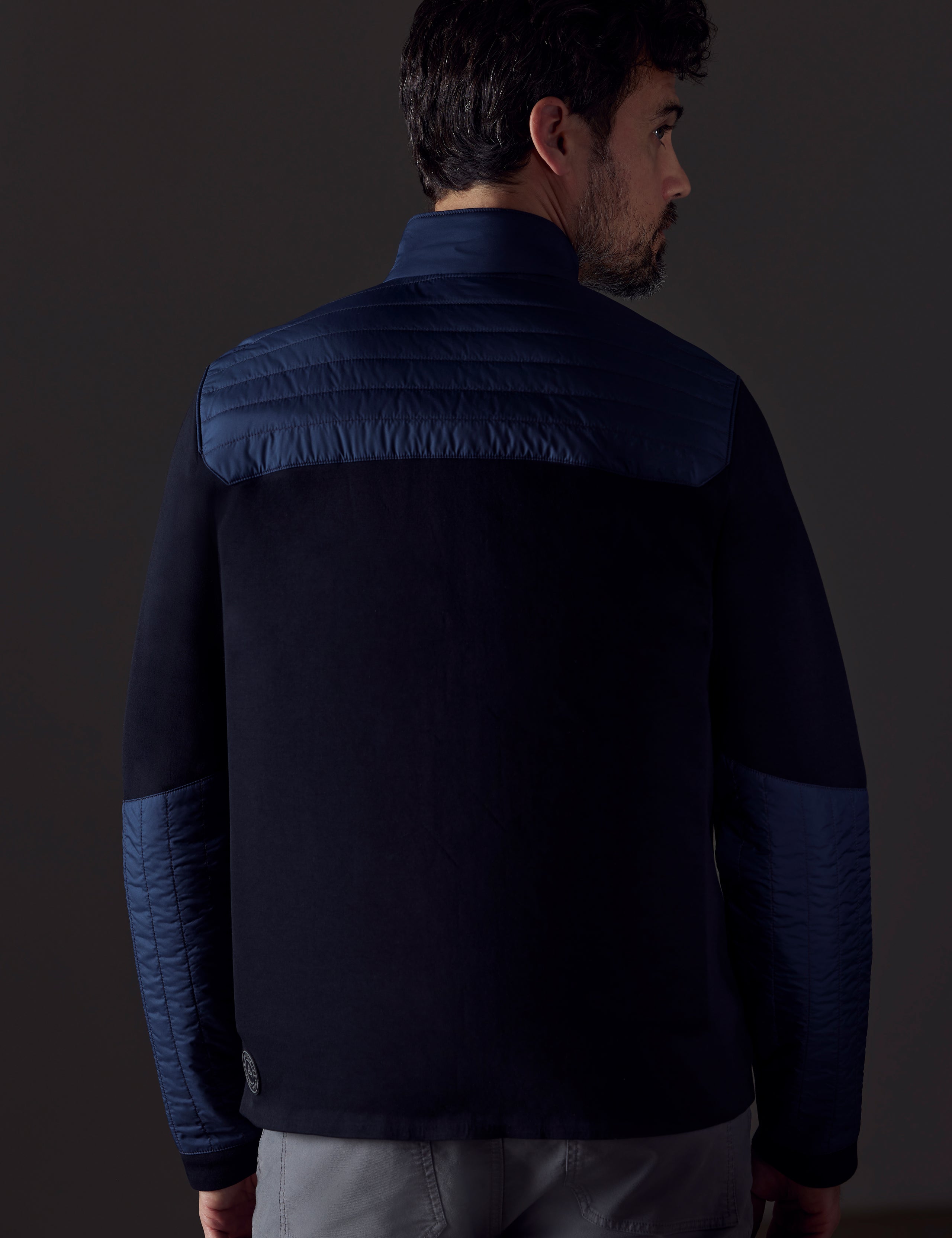 Back view of man wearing blue technical jacket from AETHER Apparel