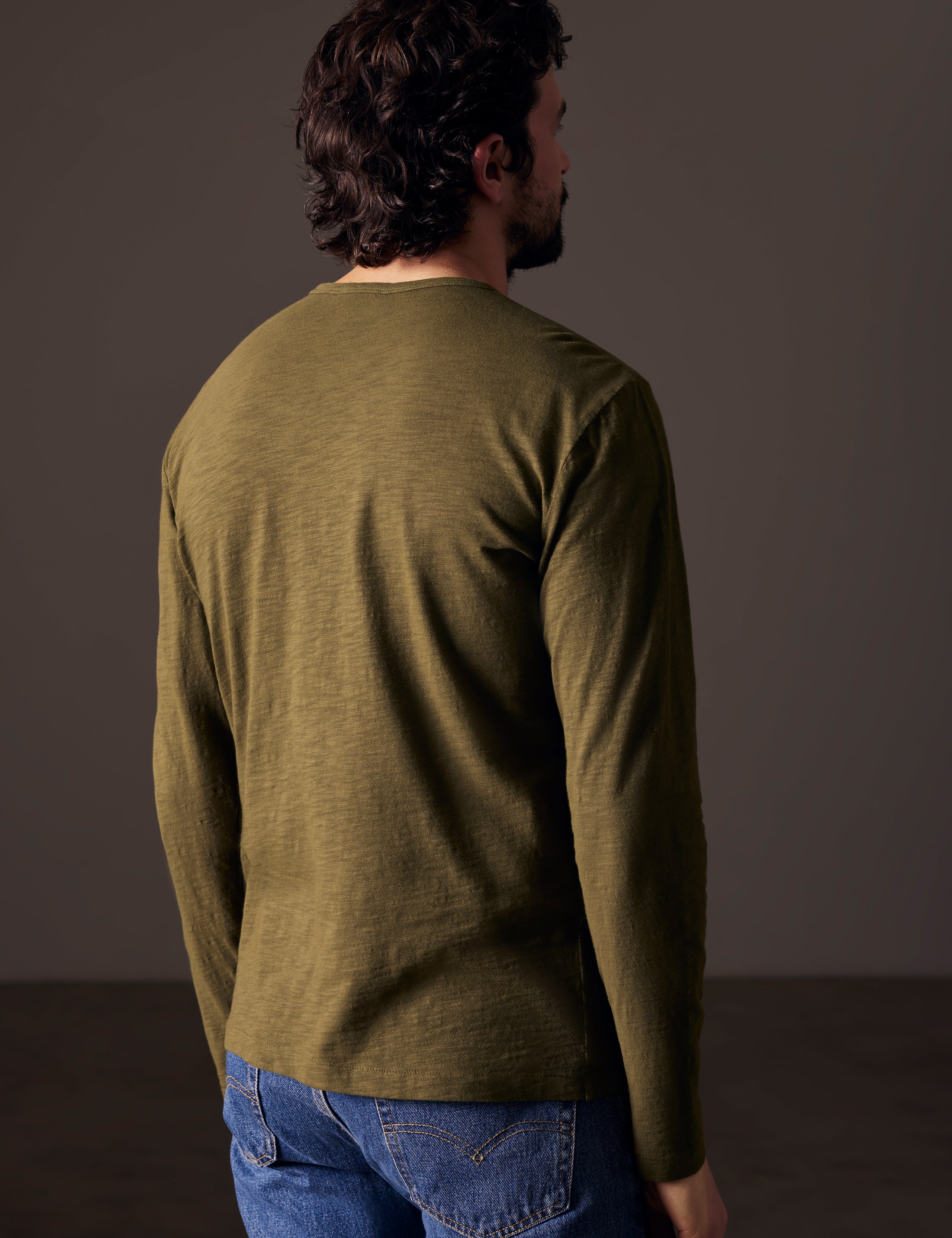 back view of man wearing green long-sleeve tee from AETHER Apparel