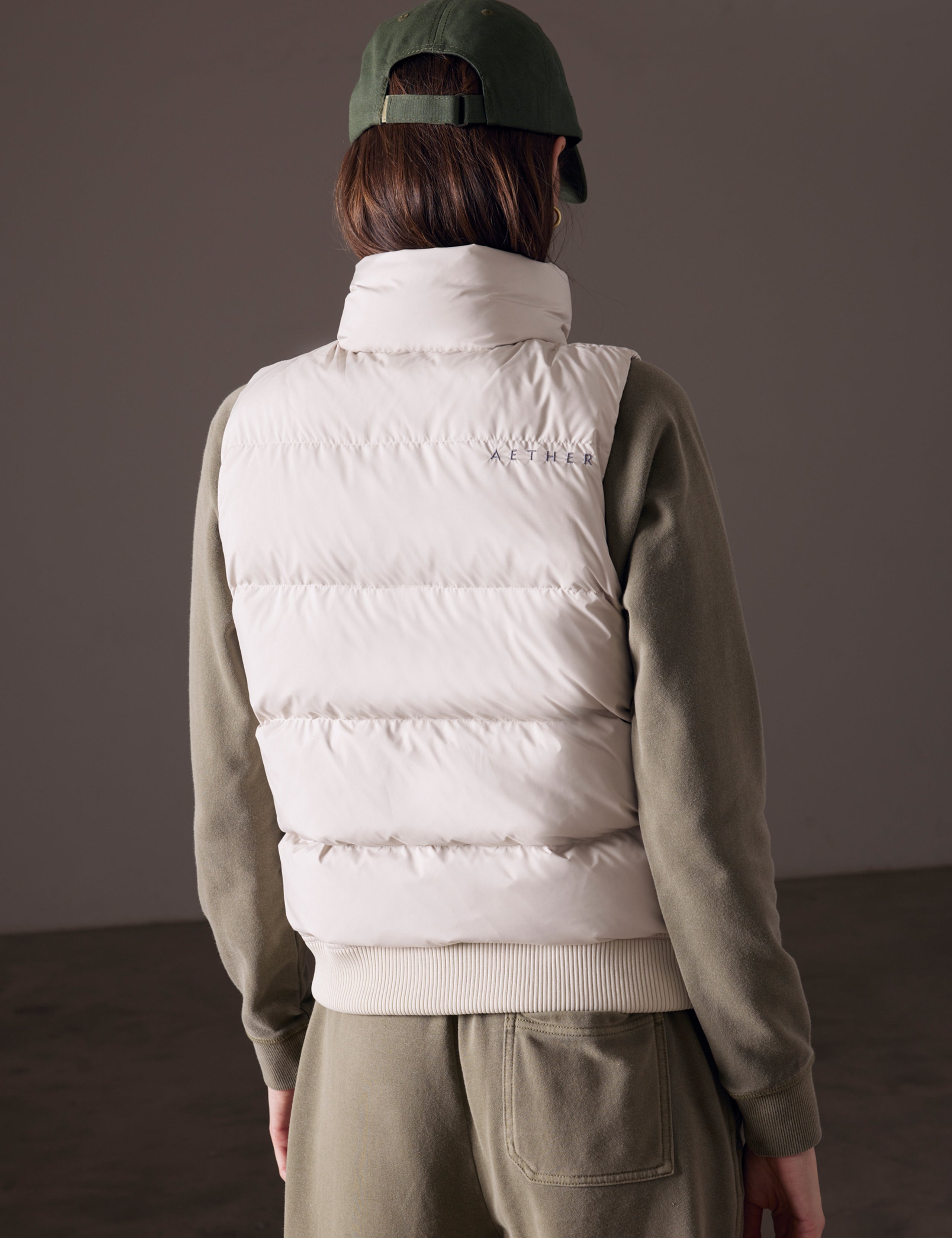 back view of woman wearing beige insulated vest from AETHER Apparel