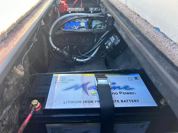 A 12-volt LiFePO4 battery securely mounted in the engine compartment of a bass boat, ready to power a day of fishing and navigation on the water.