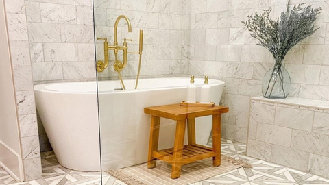 Wooden bathroom bench in front of white bathtub with The Polished Jar Charlotte Tray and dispensers