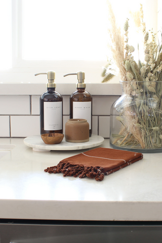 Soap bottle dispensers on tray next to hand towel